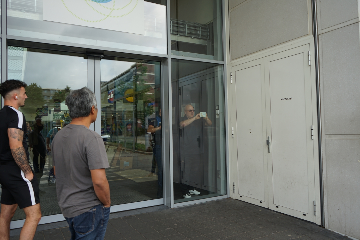 De wijkboa plakt een sticker op de deur van het winkelcentrum