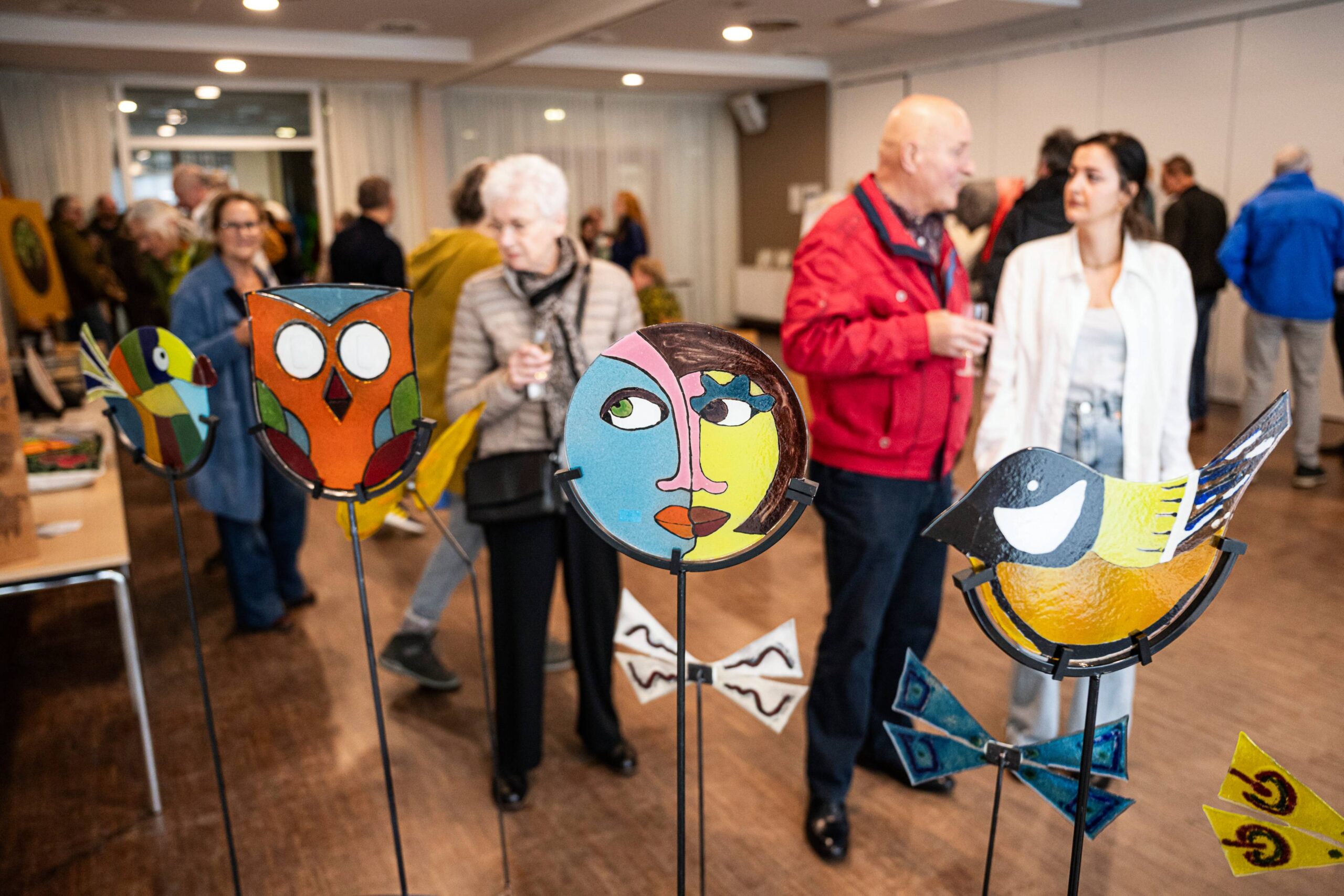 Bezoekers bekijken kunstvoorwerpen die staan uitgestald.
